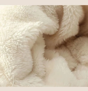 Close-up of soft cream-colored faux shearling knit fabric with a plush texture