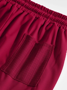 Detailed view of dark red linen pants featuring elastic waistband and textured patch pocket