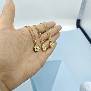 Detailed view of three gold pendant necklaces featuring shell moon, heart and cross motifs
