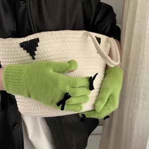 Detail of lime green knitted gloves featuring cute black bows on the knuckles for women