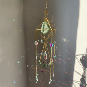 Detailed view of crystal sun catcher with green raw stone and rainbow light refraction