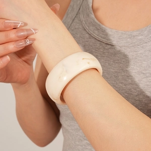Minimalist wide cream resin bangle with brown marble texture shown on a female wrist