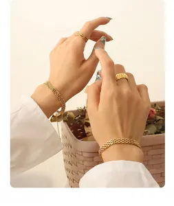 Detail von 18K vergoldetem Kettenarmband und strukturierten Ringen an der Hand