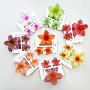 Set of colorful plumeria flower hair claws in various sizes arranged on white backdrop