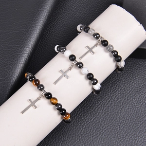 Detailed view of three tiger eye and obsidian cross bracelets on a white cylinder stand