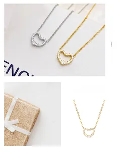 Detailed view of heart-shaped pendants with white zircon stones in gold and silver finish