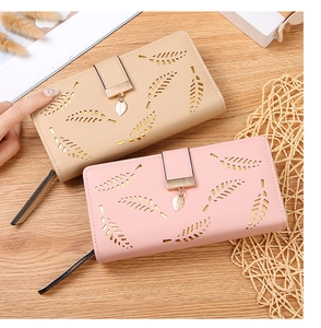 Detail of laser-cut leaf patterns on beige and pink long wallets with metal pendants