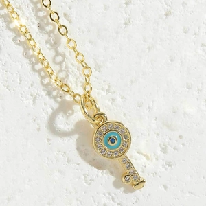 Macro shot of gold key pendant with blue evil eye symbol and pavé cubic zirconia