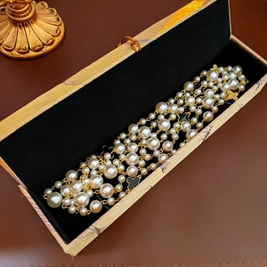 Detail of a multilayer pearl bracelet with black clover charms in a luxury box