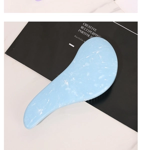 Detailed view of light blue marble pattern detangling hairbrush with ergonomic grip