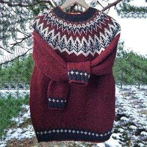 Detail of burgundy Fair Isle knit sweater with grey and white jacquard pattern textures