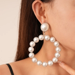 Gros plan de boucles d'oreilles créoles géométriques à perles blanches sur mannequin