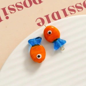 Close-up of handmade glass fish pendants with vibrant orange and blue colors