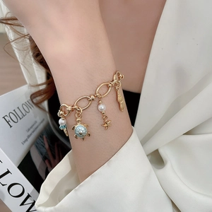 Detail of gold ocean bracelet with turtle charm and pearls on a model wrist