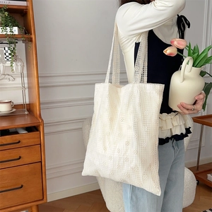 Close-up of beige lace tote bag featuring intricate floral mesh patterns and wide strap
