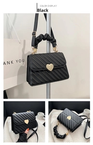 Close-up of black pleated handbag with heart-shaped gold lock and textured handle
