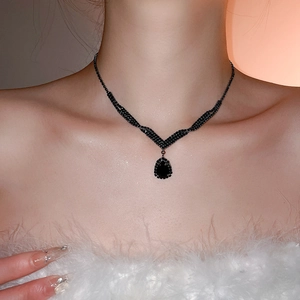 Macro view of a luxury V-shaped necklace with black teardrop crystal pendant on a model