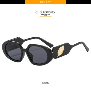 Detail of trendy oval sunglasses featuring a golden leaf metal accent on the black temple