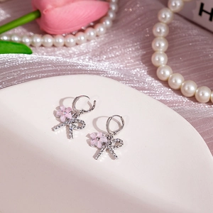 Vue détaillée des boucles d'oreilles fleur rose avec nœuds en diamants et base argent