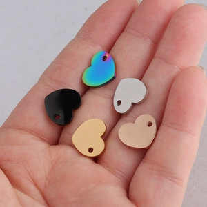 Gepolijste hartvormige hangers in regenboog, zwart, zilver, goud en roségoud op een hand