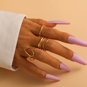 Close-up of golden titanium steel rings featuring heart cutout and layered wave designs