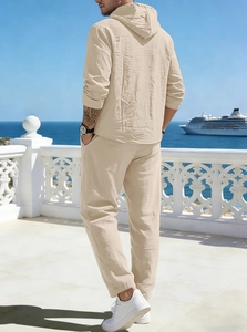 Rear view of men's beige linen set featuring hooded shirt and drawstring trousers by the sea