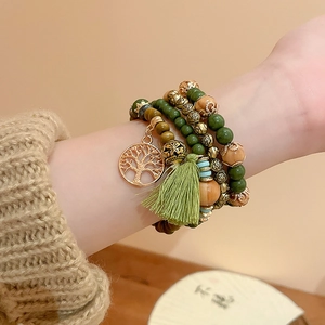 Detail of bohemian multilayer sandalwood beaded bracelet with tree of life charm and green tassel
