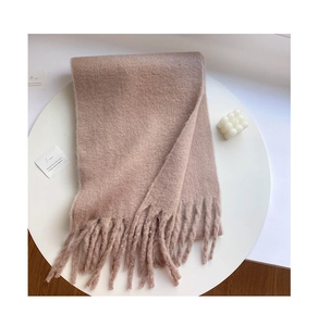 Detail view of the soft pink beige knit scarf texture with long fringe tassels