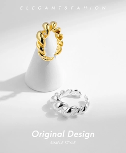 Detailed view of gold and silver twisted rope texture open rings on a minimalist white base