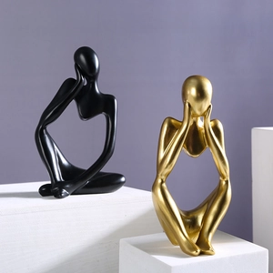 Minimalist resin thinker sculptures in black and gold on geometric display stands