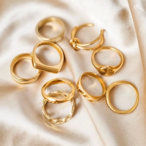 8-piece set of gold stainless steel rings with various textures on silk fabric background