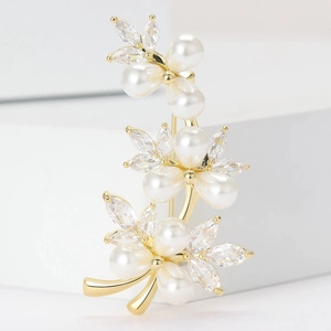 Elegant gold vine brooch with pearls and marquise cut cubic zirconia on a white background