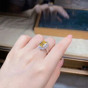 Close-up of radiant cut yellow gemstone ring with halo diamonds on female finger