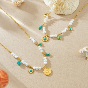 French pearl necklace with turquoise heart charms and sun pendants on a sandy background