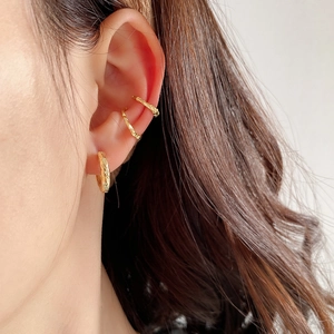 Detail of gold hammer-textured ear cuff and earring set worn on model side profile