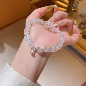 Détail d'un bracelet en perles de cristal avec breloques de lotus et cloche en argent