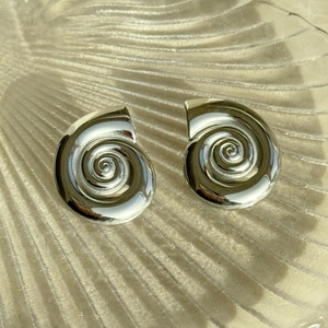 Macro view of silver polished spiral conch earrings with high-gloss metallic finish