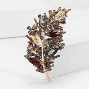 Macro shot of feather brooch with multi-colored crystals on a minimalist display