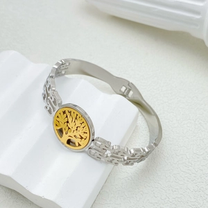 Macro shot of silver and gold stainless steel tree of life bangle on textured base