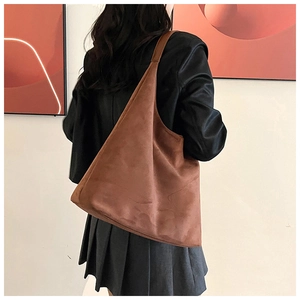 Detailed back view of a brown suede tote bag carried by a model in a warm indoor setting