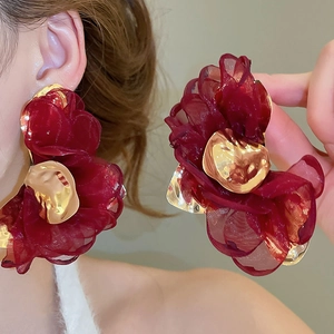 Close-up of deep red chiffon flower earrings with textured gold metal center details