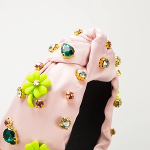Detail of pink satin headband with colorful rhinestones and green clover charms