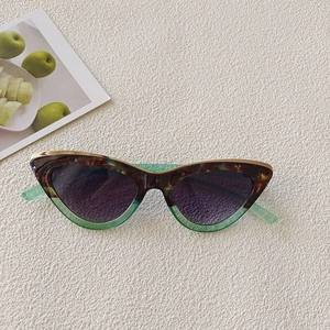 Detail of tortoise and green gradient frame sunglasses on beige textured background
