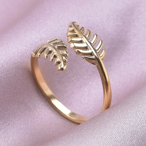 Macro shot of a gold leaf feather open ring on elegant pink silk fabric background