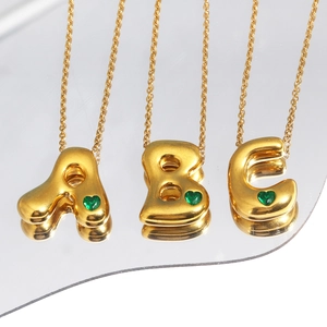 Close-up of 18k gold plated bubble letter necklaces A, B, C with green heart gems