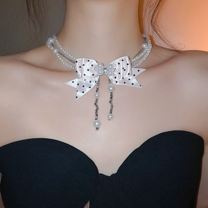 Detailed close-up of double-layer pearl necklace with a pink polka dot satin bow pendant