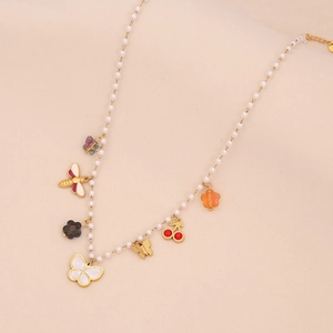 Détail du collier de perles avec breloques colorées de fleurs et papillons sur fond beige