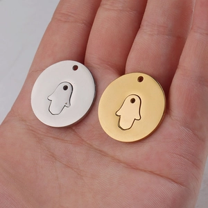 Detail of mirror polished gold and silver Hamsa Hand charms on a person's palm