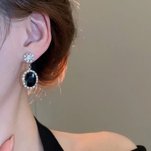 Detail view of retro flower stud earrings with black oval gemstone and zircon accents