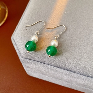 Dettaglio di orecchini vintage con agata verde e perla bianca su velluto grigio